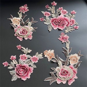 Op de afbeelding: Vier geborduurde bloemenapplicaties in roze, bruin en beige tinten. De applicaties hebben gedetailleerde bloemmotieven met delicate stiksels.