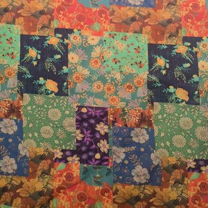 May include: A patchwork design with diverse floral patterns in a mix of colours. The squares display flowers in shades of orange, blue, green, and purple. The overall effect is a vibrant and textured textile.