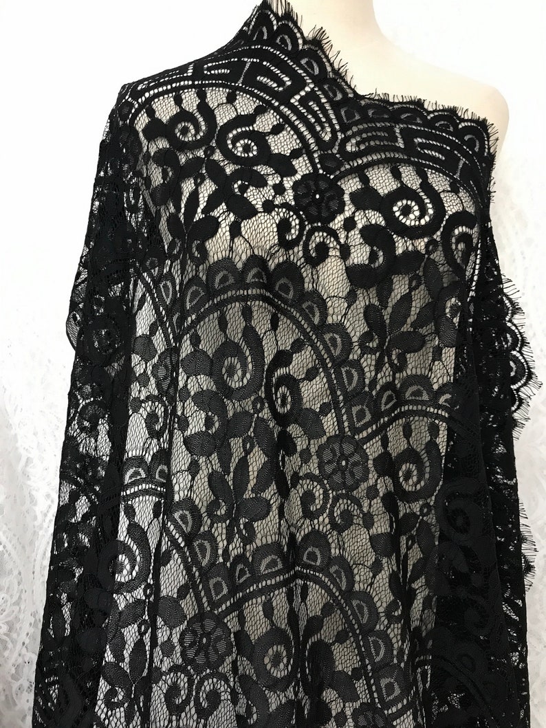 Puede incluir: Tela de encaje negra con un delicado patr&oacute;n floral. El encaje tiene un borde festoneado y es transparente.