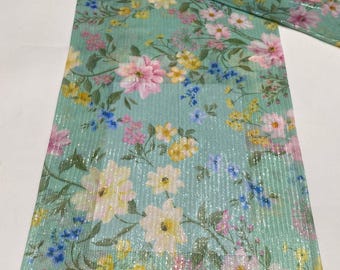 Könnte beinhalten: Ein rechteckiges Stoffpaneel mit hellminzgrünem Hintergrund und einem sich wiederholenden Blumenmuster aus rosa, gelben und blauen Blüten. Das Material weist eine dezente, vertikale metallisch silberne Streifenstruktur auf der gesamten Oberfläche auf.