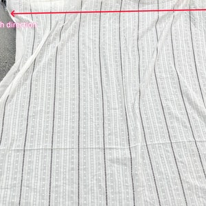 May include: White fabric with a vertical striped pattern. The fabric has a small, dotted pattern throughout.