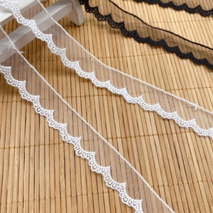 May include: White and black scalloped lace trim. The lace is delicate and has a subtle sheen. The trim is perfect for adding a touch of elegance to any project.