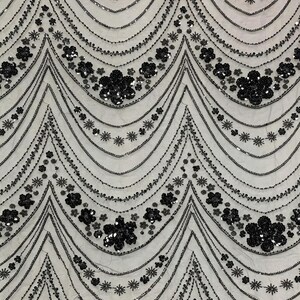 May include: Detailed shot of a fabric with a repeating pattern of black sequins and beads. The design features wavy lines with floral and starburst accents, creating a textured, elegant look. Suitable for evening wear or decorative projects.