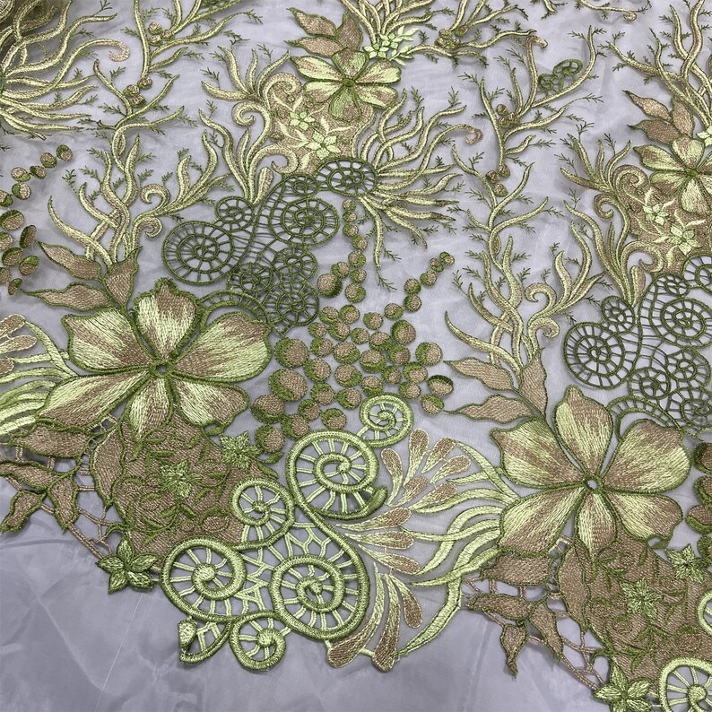 K&ouml;nnte beinhalten: Gr&uuml;ner und goldener floraler Stickerei-Spitzenstoff. Die Spitze zeigt ein zartes Blumenmuster mit Spiralen und Kreisen.