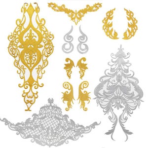 May include: A collection of embroidered lace appliques in gold and silver thread. The set includes two large vertical floral motifs, a wide horizontal lattice piece, two curved laurel-like shapes, and several smaller symmetrical scroll accents.
