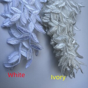 May include: Two samples of lace trim, one in white and one in ivory. Both trims feature a delicate leaf design.