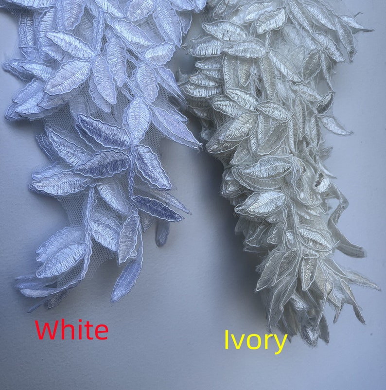 May include: Two samples of lace trim, one in white and one in ivory. Both trims feature a delicate leaf design.