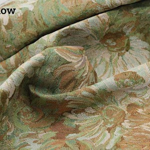 May include: A textured fabric featuring a woven floral pattern in shades of yellow, sage green, and cream. The material is draped to show its thickness and weave, with the text B: yellow printed in the upper left corner of the image.