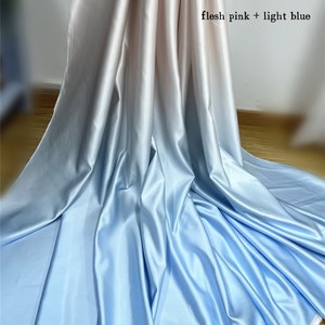May include: A length of fabric with a colour gradient, shifting from flesh pink to light blue. The material has a smooth, shiny texture, with visible folds and creases. The text "flesh pink + light blue" is visible in the upper right corner.