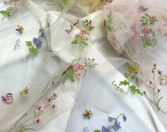May include: White sheer fabric with embroidered flowers and butterflies. The fabric has the words "Birdseed", "Violet", "Forget-me-not", "Cosmos", and "Sweet Pea" embroidered on it.