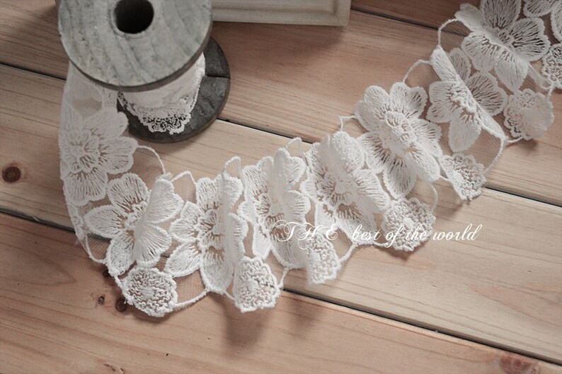 May include: White lace trim with a floral design. The lace is delicate and intricate, with small flowers and leaves.