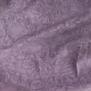 Puede incluir: Una tela de color morado claro con un delicado patrón de encaje floral en relieve. El material tiene una calidad transparente y semitransparente con pliegues y frunces suaves que crean profundidad y textura en la superficie.