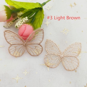 May include: Two light brown butterfly-shaped lace appliques with gold glitter accents. #3 Light Brown.