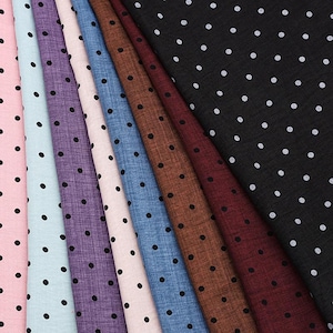 Puede incluir: Una colección de telas variadas en tonos rosa, celeste, morado, beige, azul, marrón, burdeos y negro. Cada tela presenta un patrón repetido de pequeños lunares negros espaciados. Las telas están dispuestas en diagonal.