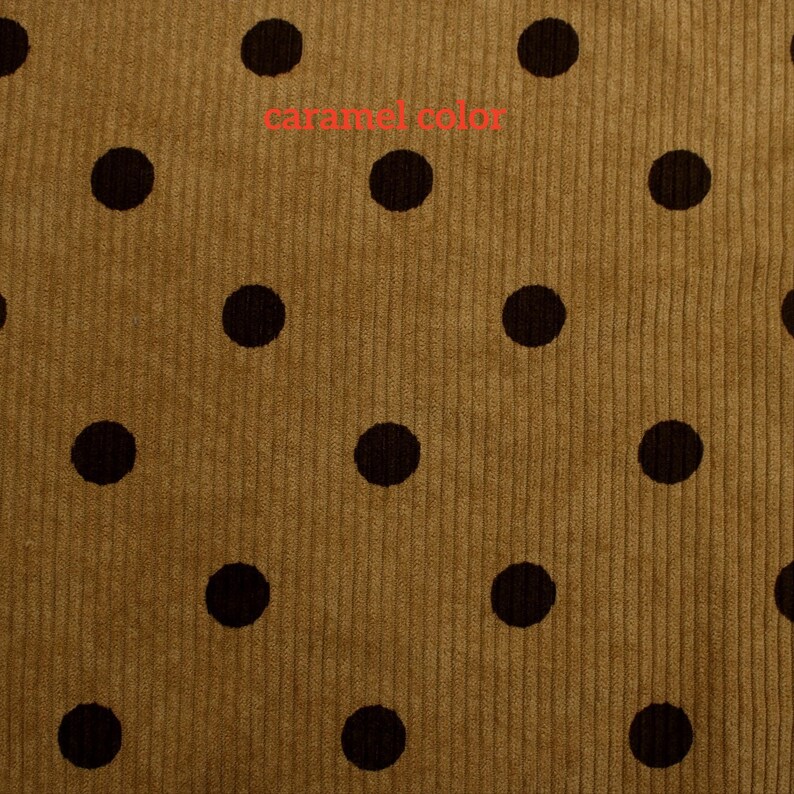May include: A caramel-colored corduroy fabric featuring a repeating pattern of dark brown polka dots. The textile has a distinct vertical ribbed texture throughout, with the text "caramel color" printed in red across the upper center area.