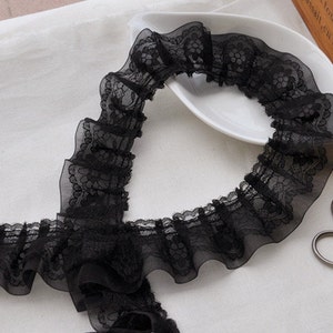 May include: Black lace trim with a ruffled edge. The lace is delicate and has a floral pattern.