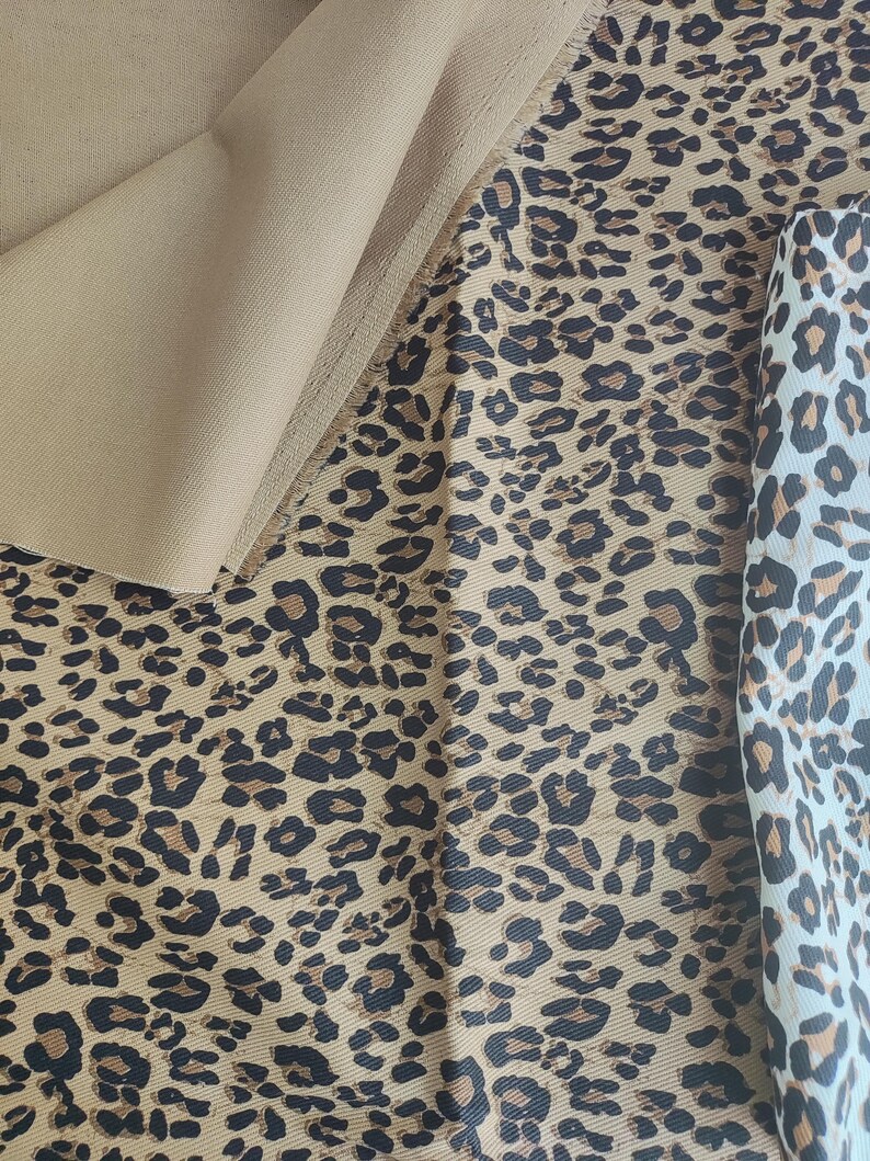 May include: Close-up of various fabrics featuring a tan solid color and leopard print patterns. The leopard prints showcase brown and black spots on a tan background, with a lighter cream-colored fabric also displaying the pattern.