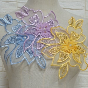 Puede incluir: Tres aplicaciones florales con lentejuelas y cuentas. Las aplicaciones son en tonos de azul, morado y amarillo.