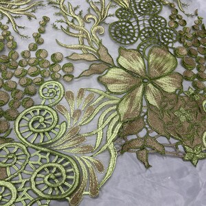 K&ouml;nnte beinhalten: Gr&uuml;ner und goldfarbener bestickter Spitzenstoff mit einem floralen und blattmuster. Die Spitze hat ein zartes, durchbrochenes Muster.