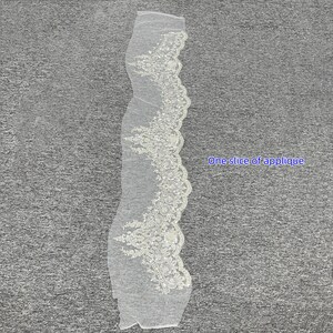 Pu&ograve; includere: Un singolo pezzo di applique in pizzo bianco con un delicato motivo floreale. Il pizzo &egrave; perlato e ha un bordo smerlato.