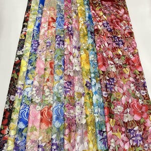 以下が含まれることがあります： 赤、黄、青、紫、ピンクなどの鮮やかな色の複雑な花柄刺繍が施された、半透明のメッシュ生地のストリップが並んでいます。それぞれの生地は、同系色または対照的な色の半透明のメッシュベースの上に重ねられています。