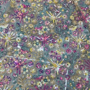 Könnte beinhalten: Ein durchsichtiger Stoff mit einem floralen Muster, das mit Pailletten in den Farben Rosa, Gelb, Blau und Grün bestickt ist.
