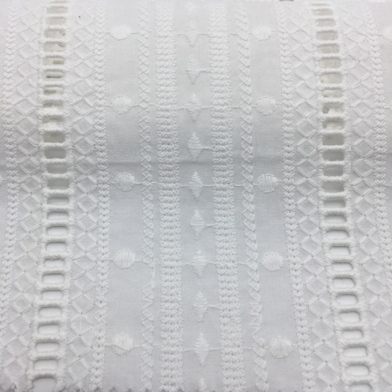 May include: White cotton fabric with an embroidered design featuring a repeating pattern of geometric shapes and circles.