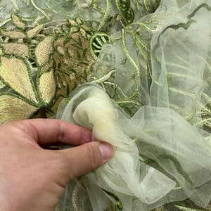 K&ouml;nnte beinhalten: Gr&uuml;ner und goldener T&uuml;llstoff mit einer zarten Blumenmuster-Stickerei.