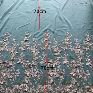 Pu&ograve; includere: Un tessuto di tulle azzurro chiaro con ricamo di farfalle 3D rosa. Il tessuto misura 70 cm x 70 cm.