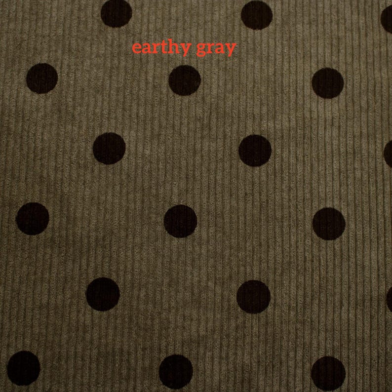 May include: A textured corduroy fabric in an earthy gray tone featuring a repeating pattern of solid dark brown polka dots. The surface displays vertical ribbed lines characteristic of corduroy material, with the text earthy gray visible.