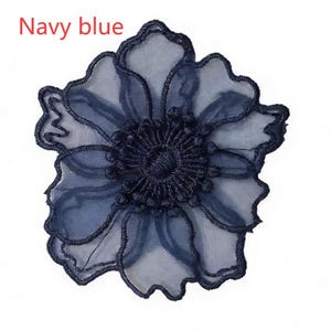 May include: A navy blue flower applique featuring sheer, translucent petals with embroidered edges and a dense, textured center. The text "Navy blue" is printed in the upper left corner of the image, identifying the color of the floral design.