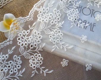 May include: White lace trim with a delicate floral pattern. The lace is made of a sheer fabric with small holes throughout. The trim is perfect for adding a touch of elegance to any project.