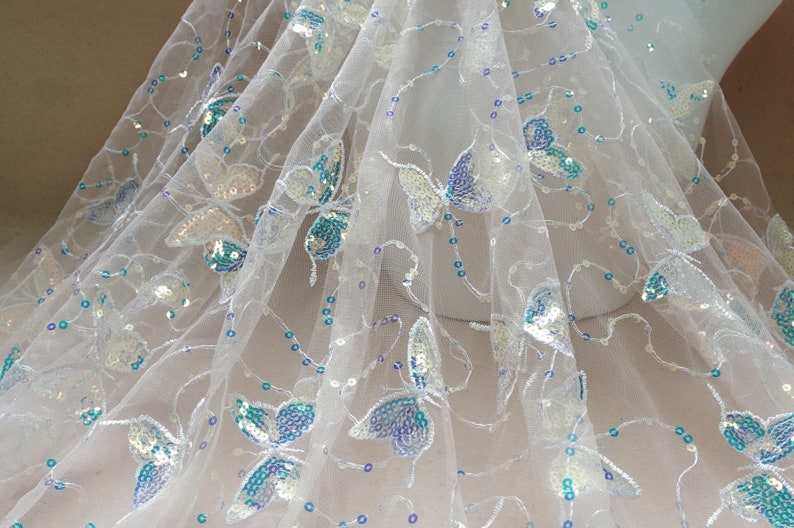 May include: White tulle fabric with iridescent sequins and blue butterfly designs.