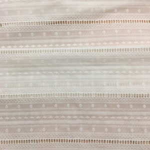 May include: White cotton fabric with a delicate embroidered pattern. The pattern features a repeating design of small circles, diamonds, and lines.