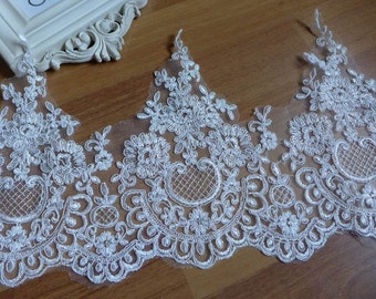 May include: White lace trim featuring a delicate floral design. The lace has a scalloped edge and is sheer and lightweight.