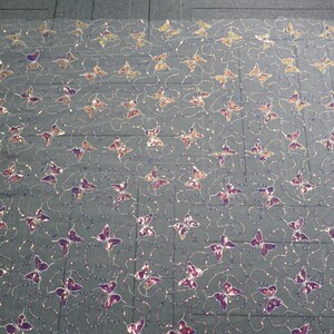May include: A sheer fabric with a repeating pattern of purple and gold butterfly sequins. The fabric is white and has a subtle shimmer.