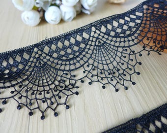May include: Black lace trim with a scalloped edge and a geometric pattern. The lace has a delicate, intricate design.