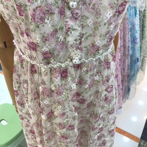 May include: A white lace dress with a floral print and a pearl and rhinestone embellishment at the waist.