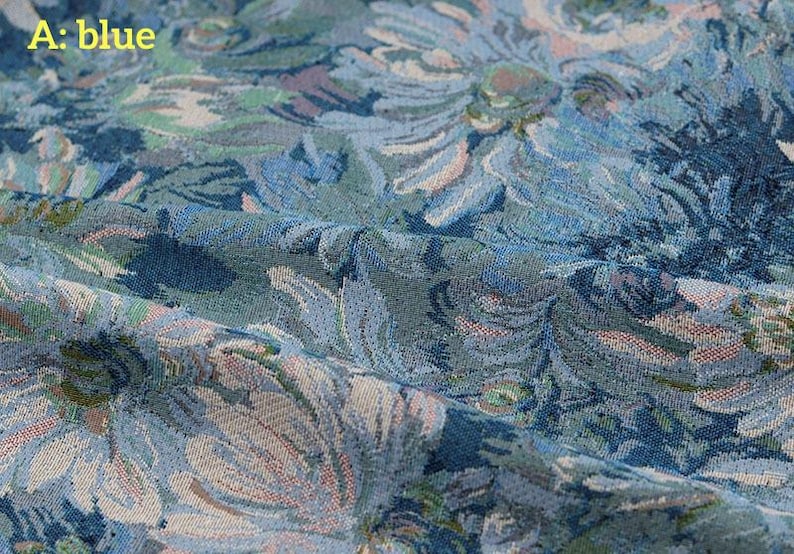 May include: A blue fabric featuring a woven floral pattern with shades of light blue, dark blue, and hints of muted green and cream. The textile displays a dense, textured weave with visible folds and the text A: blue in the upper left corner.