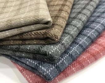 Puede incluir: Una pila de muestras de tela a cuadros en varios colores, incluyendo beige, marrón, gris, azul y rosa. Cada tela tiene un patrón de cuadros con detalles blancos. Las telas están dobladas y superpuestas, mostrando sus texturas y variaciones de color.