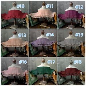 May include: A collection of nine pleated fabric collars in various colors, displayed on mannequin busts. Colors include red, peach, purple, gray, pink, and green. Each collar is labeled with a number from #10 to #18.