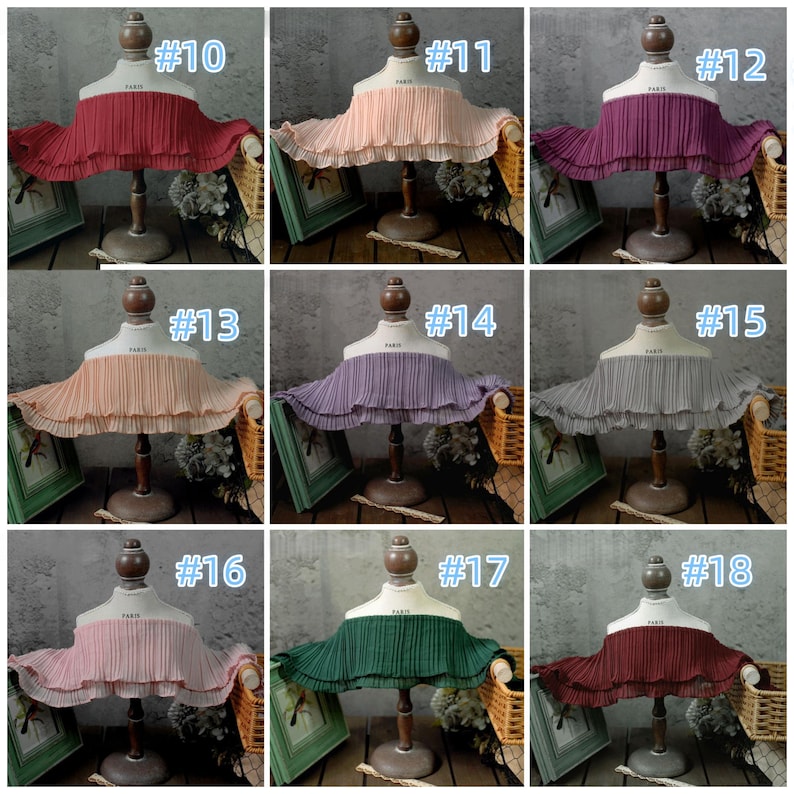 May include: A collection of nine pleated fabric collars in various colors, displayed on mannequin busts. Colors include red, peach, purple, gray, pink, and green. Each collar is labeled with a number from #10 to #18.