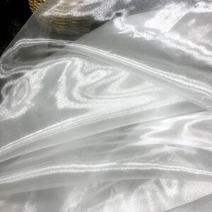 K&ouml;nnte beinhalten: Wei&szlig;er, durchsichtiger Stoff mit glatter, seidenartiger Textur. Der Stoff ist durchscheinend und hat einen leichten Glanz.