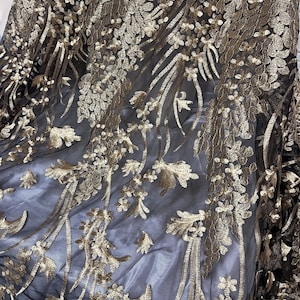 May include: Black sheer fabric with gold floral embroidery. The embroidery is intricate and detailed, creating a luxurious look.