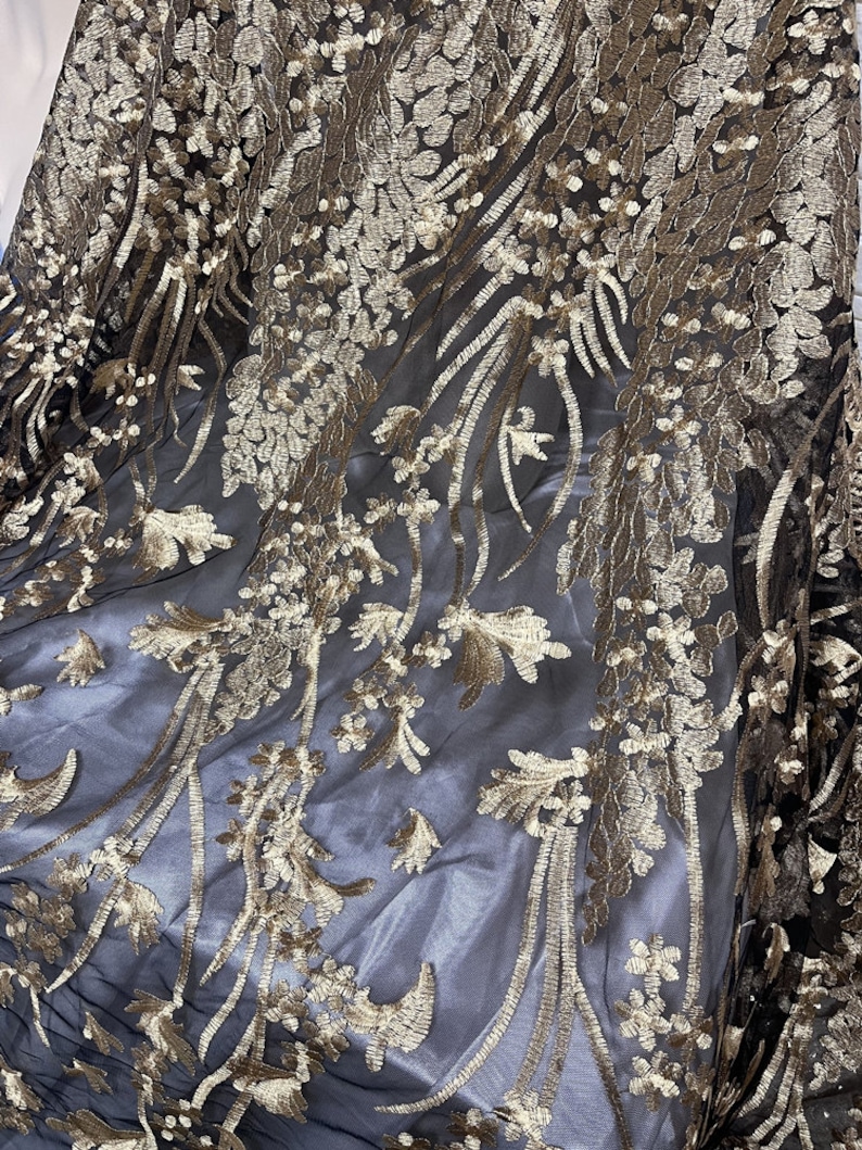 May include: Black sheer fabric with gold floral embroidery. The embroidery is intricate and detailed, creating a luxurious look.