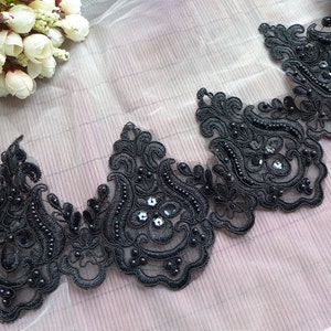 Può includere: Bordino in pizzo nero con decorazioni perlate. Il bordino presenta un delicato motivo floreale con piccole perline nere e paillettes.