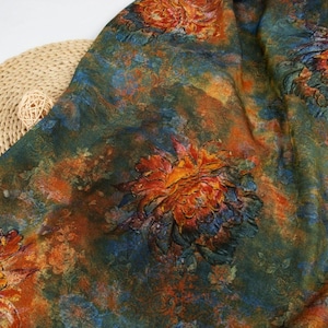 May include: A piece of fabric featuring a dark, moody floral print with large, textured-looking blossoms in shades of burnt orange, deep red, and golden yellow, set against a background of blended dark green, navy blue, and earthy brown tones.