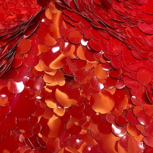 Puede incluir: Una densa disposici&oacute;n de lentejuelas circulares de color rojo brillante superpuestas entre s&iacute;. La superficie presenta un acabado met&aacute;lico reflectante con diversos tonos de rojo brillante y profundo, creando un patr&oacute;n texturizado y superpuesto.