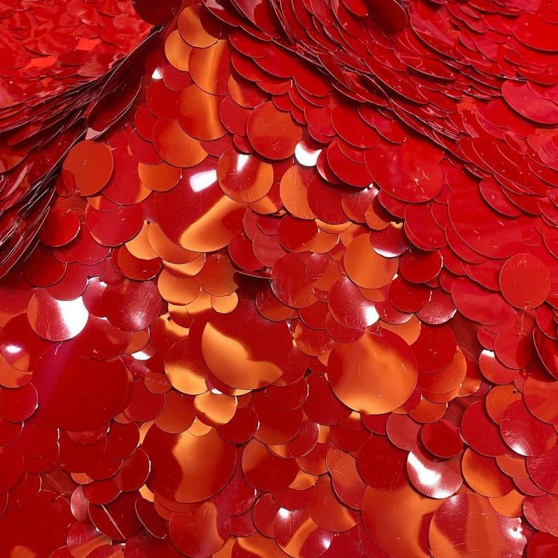 Puede incluir: Una densa disposici&oacute;n de lentejuelas circulares de color rojo brillante superpuestas entre s&iacute;. La superficie presenta un acabado met&aacute;lico reflectante con diversos tonos de rojo brillante y profundo, creando un patr&oacute;n texturizado y superpuesto.