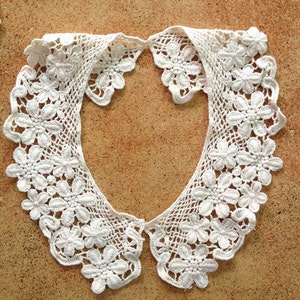 May include: White crocheted lace collar with a scalloped edge and floral design.